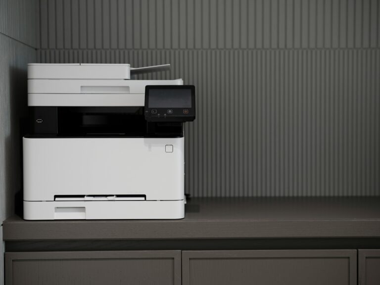 A sleek, modern printer situated on a minimalist office desk with a textured background.